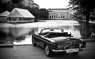 grayscale photography of a convertible coupe near lake