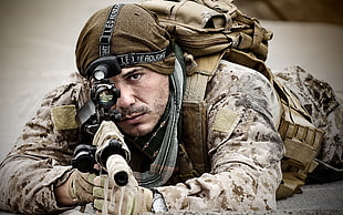 man wearing brown camouflage holding rifle photo