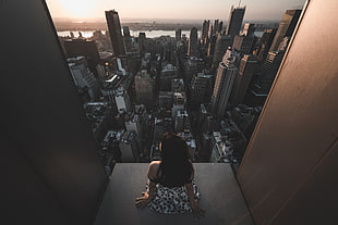 woman sitting in building facing cityscape
