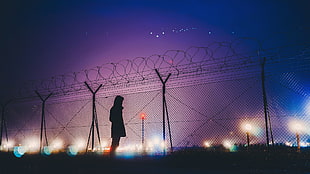 woman standing near fence with lighted posts