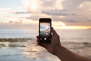person taking a photo of sunrise using iPhone during daytime HD wallpaper