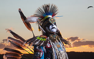 tribe man in feather  outfit during sunset