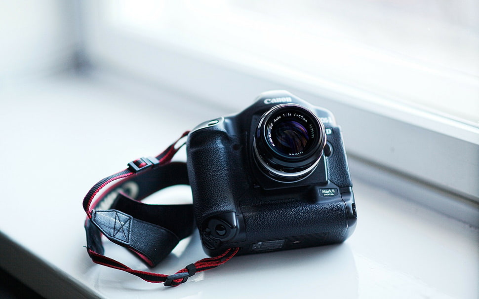 black and gray Canon DSLR camera on white surface HD wallpaper