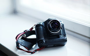 black and gray Canon DSLR camera on white surface
