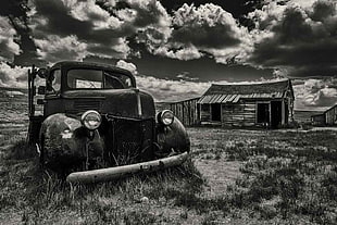 greyscale photo of classic car under cloudy sky