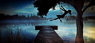 Silhouette of woman riding on swing near river dock and tree at night