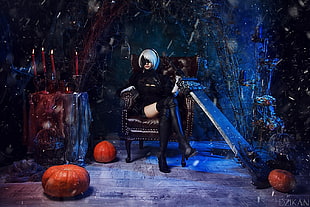 woman wearing black leather thigh-high boots sitting on chair surrounded by pumpkins
