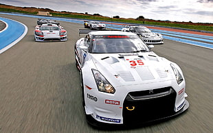 white Nissan GTR Skyline leading the pack while being chased by other race cars on track HD wallpaper