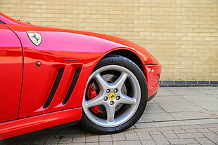 red Ferrari sports car parked near brown brick wall