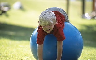boy wearing red crew neck shirt on stability ball