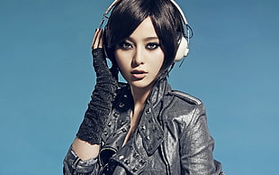 woman in black leather jacket listening on white headphones