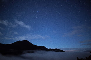 mountains cover by clouds under stars