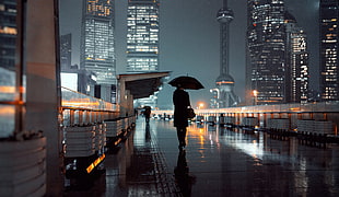 person holding umbrella walking on street during nightime