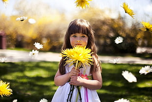 selective focus photography of girl holding yellow flower