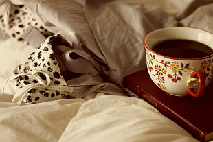 coffee filled in teacup on wooden table beside blanket