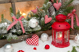red candle lantern beside baubles and tinsel with snow