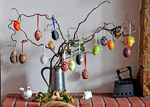 grey stainless steel pitcher with faberge eggs hanging on tree twigs
