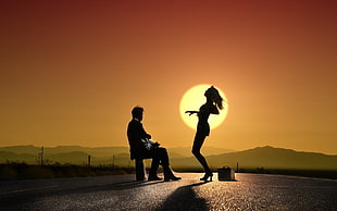 man playing guitar sitting on bench infront of woman dancing on road during golden hour