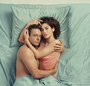 two person hugging on gray bed sheet