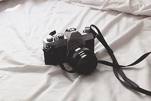 black and gray DSLR camera on white textile