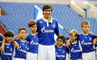 man wearing blue and white soccer jersey with six boys in the same uniform