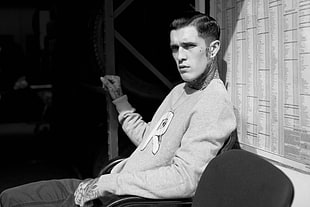 grayscale photography of man in sweatshirt sitting
