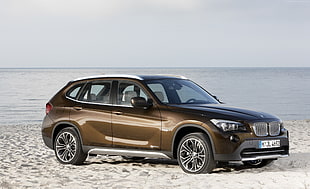 brown BMW SUV on white beach sand
