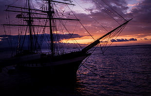 silhouette of ship on body of water during sunset