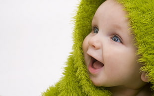 baby in green towel smiling taking portrait