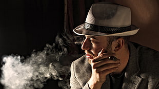 man in beige and black fedora hat holding brown cigar