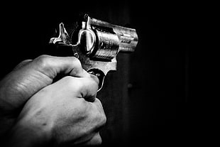 close up photo of person hand holding revolver