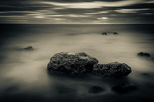 grayscale photography of stones on sea