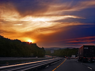 red container van on highway at sunset