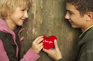 man and woman holding heart-shape plush toy
