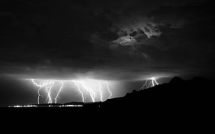 grayscale photo of lightning near mountain