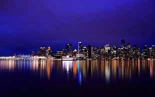 city skyline with reflection of water during nighttime HD wallpaper