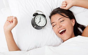 woman waking up near alarm clock