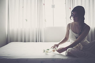 woman holding white flower accent headband sitting on bed