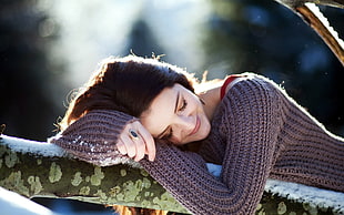 selective focus photography of woman wearing gray knit sweater laying on white wooden surface