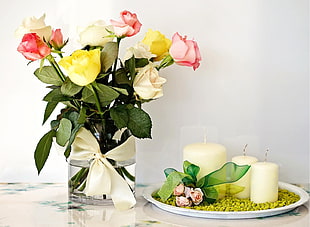 roses in vase beside candles