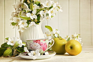 green apples; white and pink floral ceramic teacup; white flowers