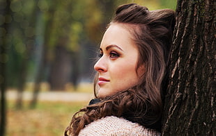 woman with brown hair in front of a brown tree trunk