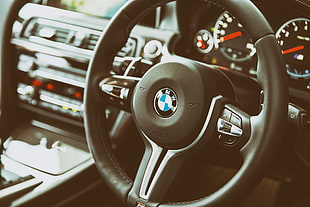 focus photography of black BMW steering wheel
