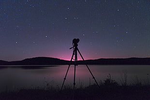 silhouette of camera stand with mountain view and nebula photography