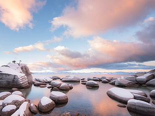 snow covered rocks on body of water under blue and white cloudy sky during daytime, lake tahoe