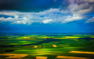 aerial photo of greenfields during cloudy day
