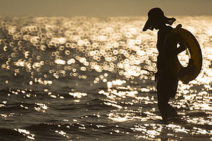 silhouette if person in the body of water during sunset
