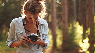 shallow focus photograph of woman holding camera