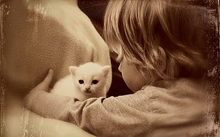 girl wearing gray sweater near white kitten