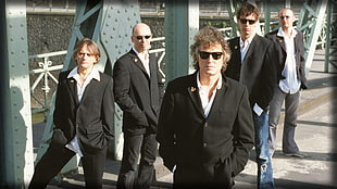 five men in black suit jacket standing on road